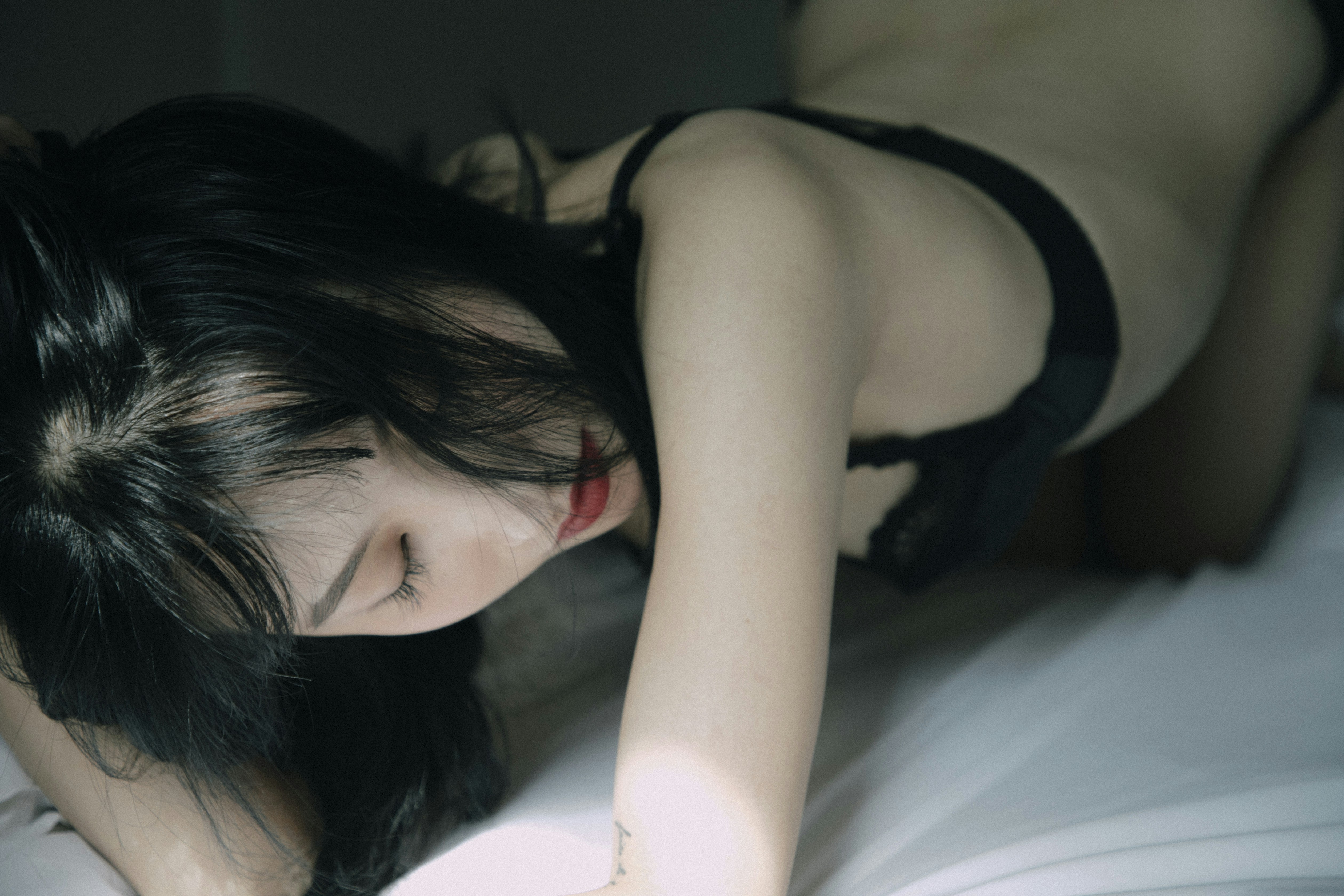 a woman laying on top of a bed in a black bra